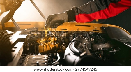 Mechanic checking engine oil level with dipstick in car engine. Automotive maintenance, inspection and professional service concept in workshop.