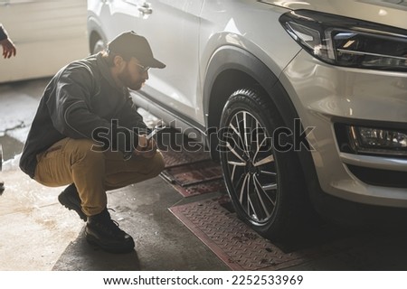Mechanic checking geometry and suspension of a car wheel using precision tools. High-quality photo