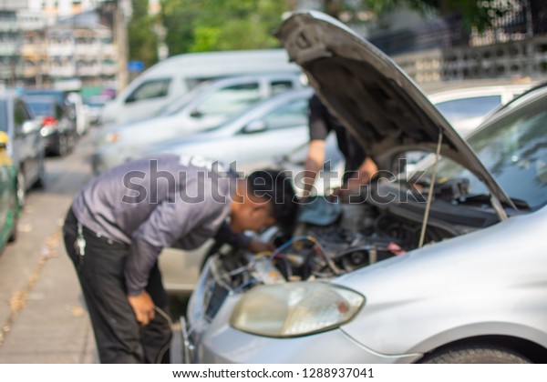 Mechanic checking and maintenance car in car\
service. subject is\
blurred.