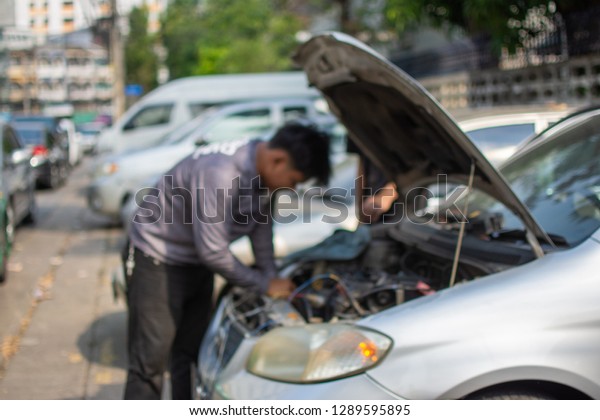Mechanic checking and maintenance car in car\
service. subject is\
blurred.