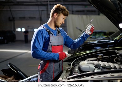 Mechanic Checking Oil Level In A Car Workshop