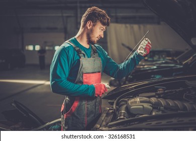 Mechanic checking oil level in a car workshop