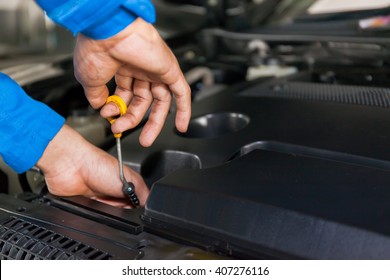 Mechanic checking oil level in a car service garage - Powered by Shutterstock