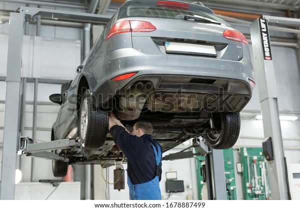 Mechanic checking oil level in car\
engine. Automobile on mechanical lift. Special equipment for\
diagnostic. Service station and machine maintenance\
concept