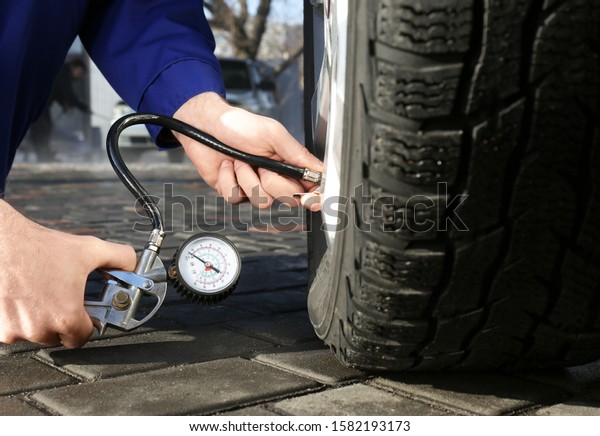Mechanic checking tire air pressure at car\
service, closeup