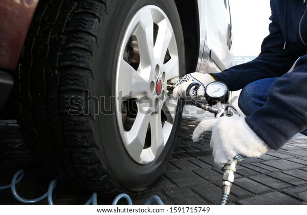 Mechanic checking tire air pressure at car\
service, closeup