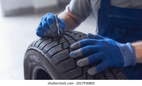 Mechanic checking tire tread depth and wear using a tire gauge, car maintenance concept