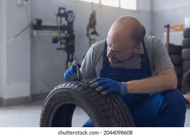 Mechanic Checking Tire Tread Depth And Wear Using A Tire Gauge, Car Maintenance Concept