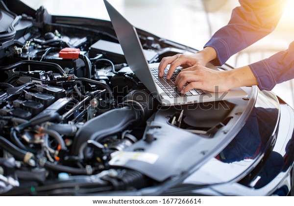 Mechanic checks the car\
engine with electronic tools. Modifying the engine with a computer\
Check service