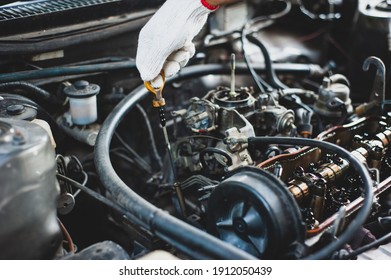 A mechanic checks the car and engine oil.