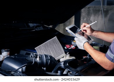 The mechanic checks the engine using tablet computer technology. Complete with wrench tool Auto mechanic working in the garage. Repair service.