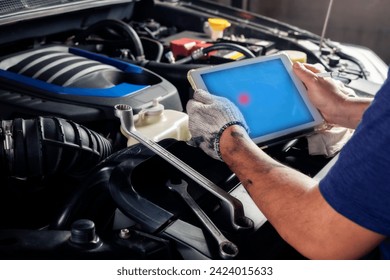 The mechanic checks the engine using tablet computer technology. Complete with wrench tool Auto mechanic working in the garage. Repair service. - Powered by Shutterstock - Get 15% off with code: PIKWIZARD15