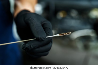 The mechanic checks the oil in the car engine. Close-up of a hand holding a dipstick - Powered by Shutterstock