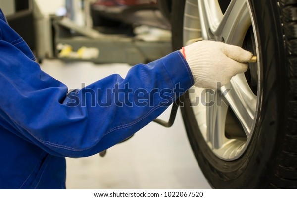 Mechanic checks the tire pressure of the car,\
pressure gauge, hands