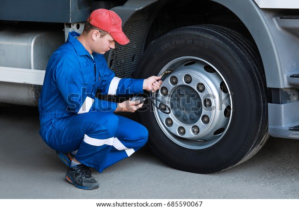 A mechanic\
checks the tire pressure gauge\
truck