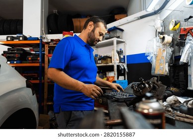 Mechanic choosing tools from a set while working on a car component in a busy garage