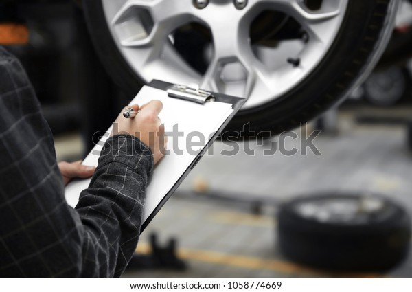 Mechanic with\
clipboard at tire service,\
closeup