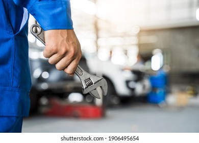 Mechanic close up fixing repairing car engine automobile vehicle parts examining screwing using tools wrench equipment working hard in workshop garage support and service in overall work uniform - Shutterstock ID 1906495654