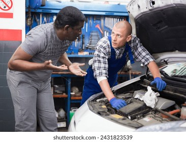 The mechanic communicates with the client about his car at auto car repair service center - Powered by Shutterstock