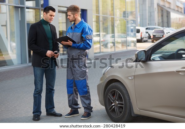 Mechanic and Customer Discussing Problem With Car.\
Auto Repair Shop