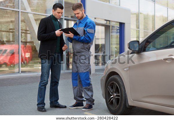 Mechanic and Customer Discussing Problem With Car.\
Auto Repair Shop