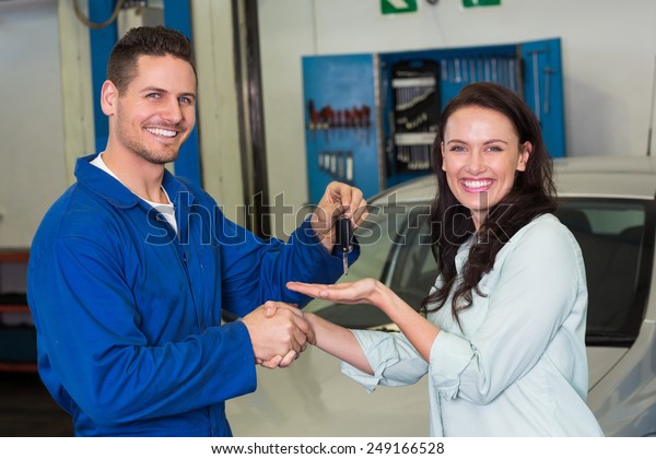 Mechanic and customer smiling at camera at the\
repair garage