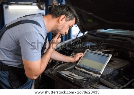 Mechanic diagnosing a car using a computer in a workshop
