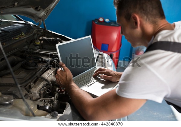 Mechanic with diagnostic tool in car workshop\
checking problem