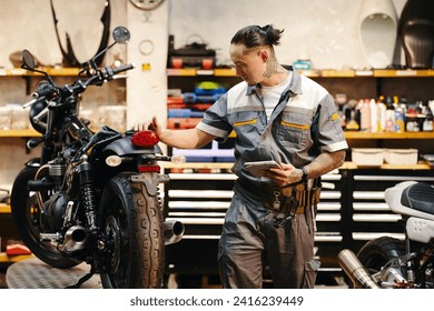 Mechanic with digital tablet examining motorcycle of client and filling form on tablet - Powered by Shutterstock