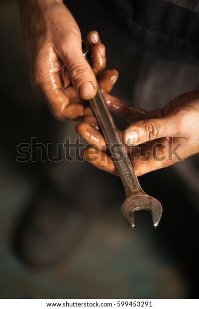 Mechanic. Dirty hands holding\
wrench.