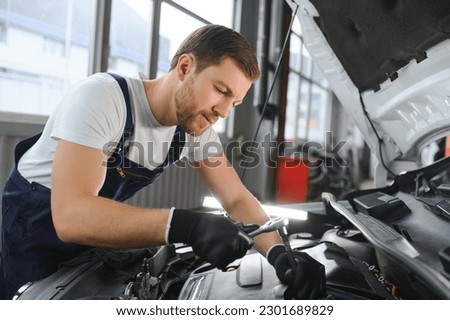 A mechanic is doing car checkup under the hood with flashlight at mechanic's shop Foto stock © 