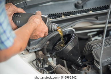 Mechanic Draining Engine Oil From A Car For An Oil Change At An Auto Shop