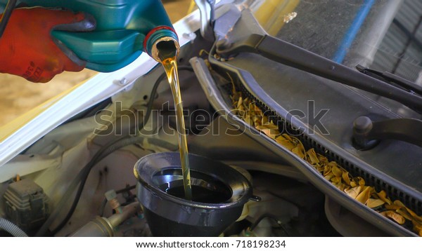 Mechanic draining engine oil from a car for an oil\
change at an auto shop