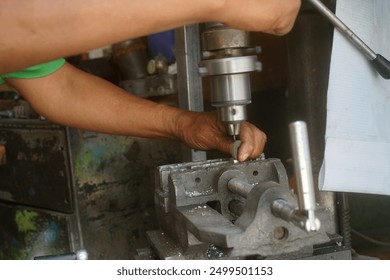  a mechanic is drilling small metal piece                                       - Powered by Shutterstock