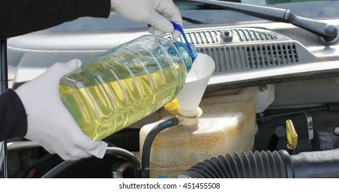 Mechanic Or Driver Adding Coolant With Antifreeze Additive To Car Or Truck Engine.  Routine Maintenance Filling Up The Ethylene Glycol Fluids To Proper Levels.