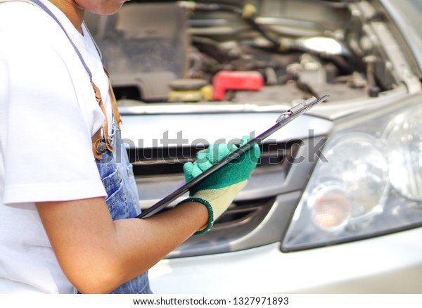 Mechanic or Engine\
technician  checking according to the technical system list of a\
car. Repair service.