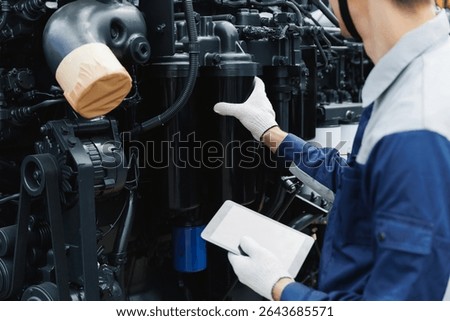 Mechanic engineer with tablet computer inspecting and fix engine from industrial mining truck, diesel injector adjustment and filter replacement.