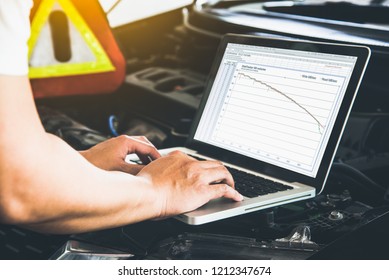 Mechanic engineer using computer laptop analyze car engine perfermance test in workshop, Car automotive concept