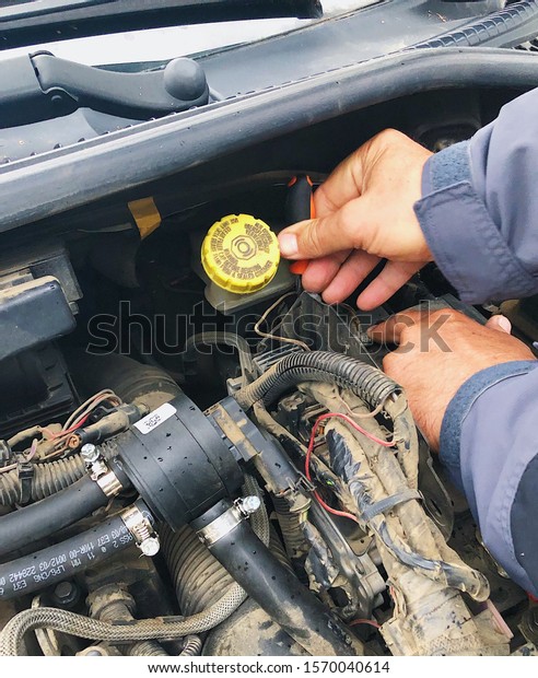 Mechanic\
examining car engine under hood close up\
