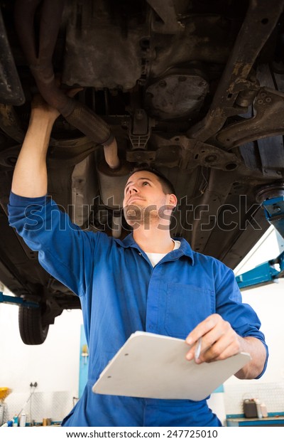 Mechanic\
examining under the car at the repair\
garage