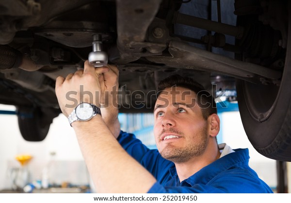 Mechanic\
examining under the car at the repair\
garage