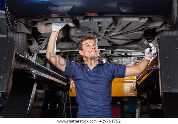 Mechanic Examining\
Underneath Lifted Car