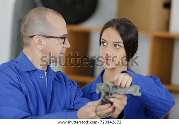 mechanic and female\
trainee working\
together