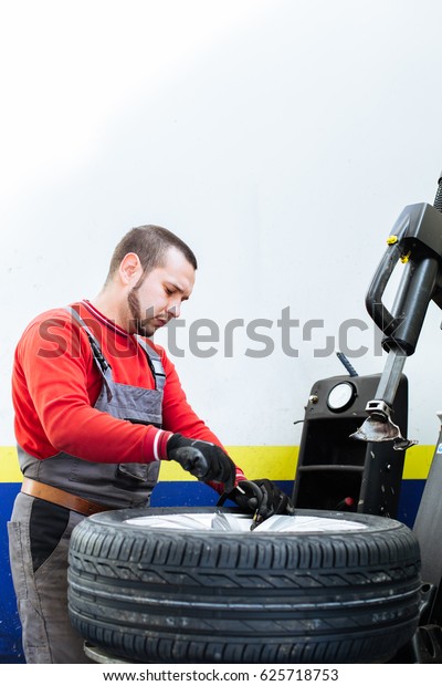 Mechanic filling air in the\
tire and removes car tire. Machine for removing rubber from the\
wheel disc