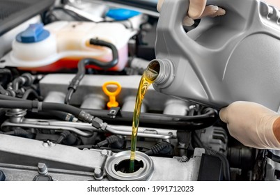 Mechanic fills up the car engine with motor oil - Shutterstock ID 1991712023
