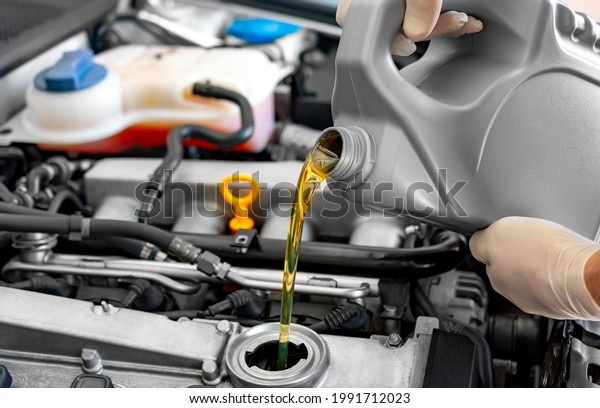 Mechanic fills up\
the car engine with motor\
oil