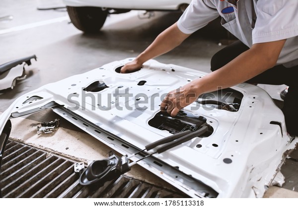mechanic fixing car door and body paint\
with soft-focus and over light in the\
background