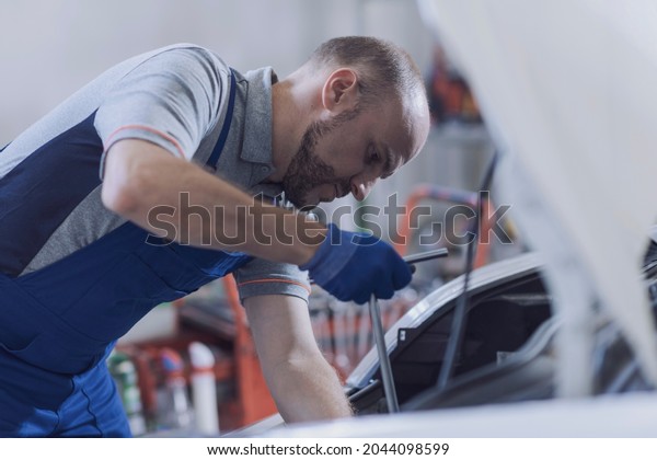 Mechanic
fixing a car engine in the auto repair
shop
