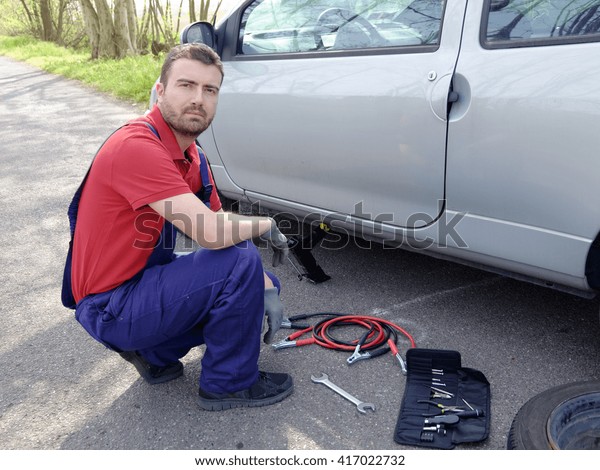 mechanic fixing a car\
problem on the road