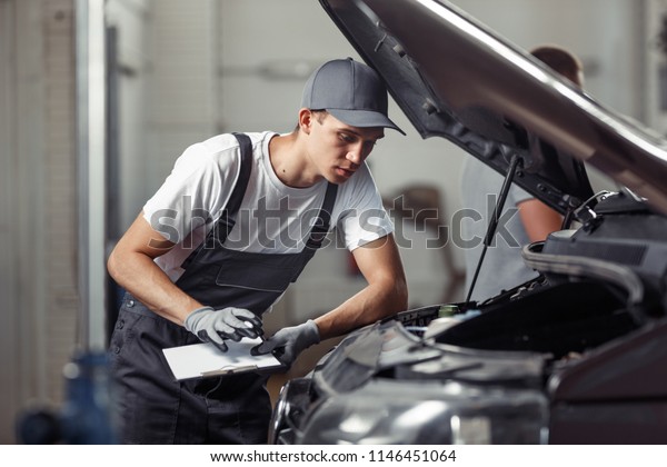 A mechanic is\
fixing a car at a car service
